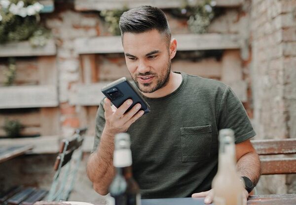 man in gray crew neck long sleeve shirt holding black smartphone