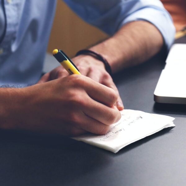 Free Person Writing on Paper Using Yellow and Black Pen Stock Photo