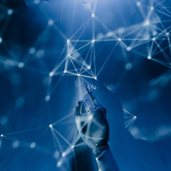 Free A robotic hand reaching into a digital network on a blue background, symbolizing AI technology. Stock Photo